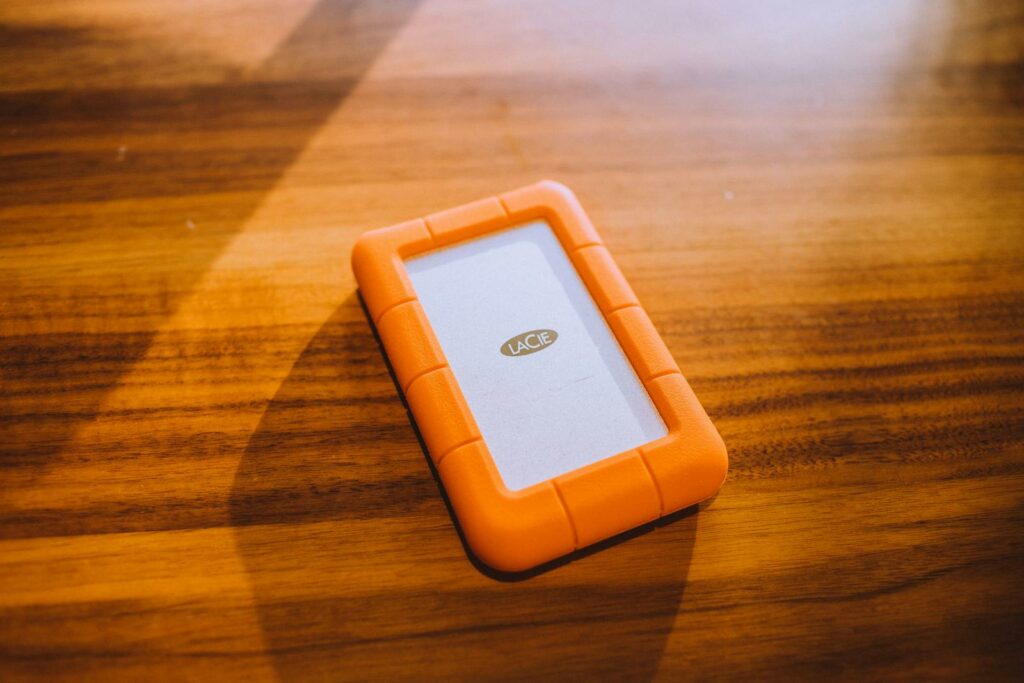 Close-up of an orange portable hard drive on a wooden table, perfect for tech and business themes.